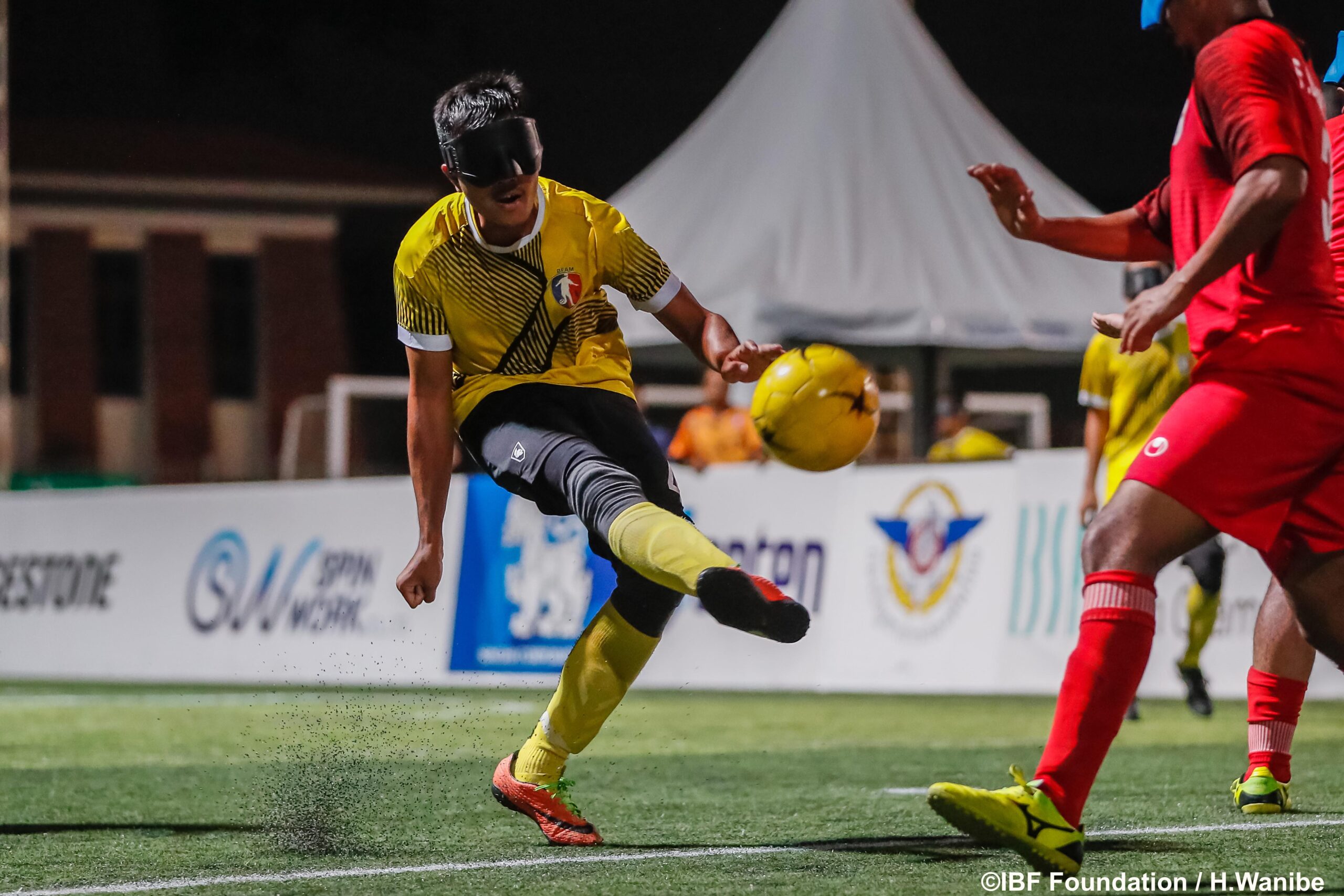 A blind football player strikes the ball into the air